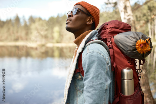 Guy astonished by magnificent nature. Afro american wanderer with backpack with tent ready for forest adventures. Seek for new experience, travelling alone, new horizons concept. Copy space