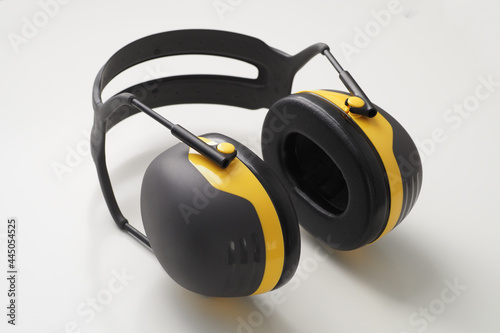 Yellow ear muffs on white desk. Protective headphones.