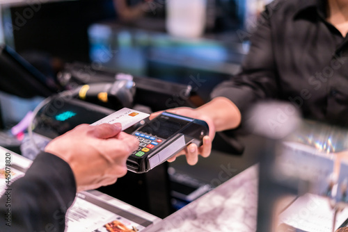 Money,Financial and pay technology concept.Business man holding credit card reader machine and customer paying money with contactless credit card with NFC technology to pay.