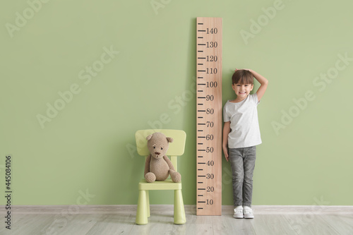 Little boy measuring height near color wall