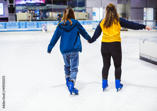 Girl friends ice skating on the ice rink together