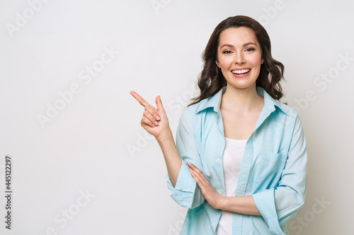 Young woman smiling and gesturing to copy space.