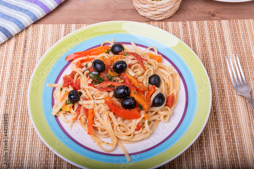 Linguini pasta with pepper, basil and olive sauce - portion in a plate, close-up