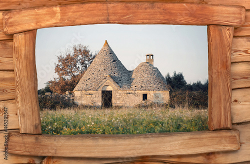 An abandoned Italian trullo (trulli), a country house of peasants in southern Italy, seen through a wooden window frame. Medium shot. 