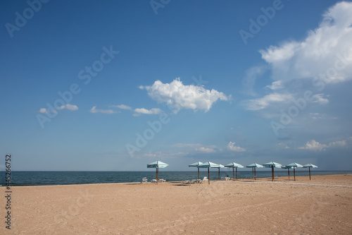 Sunshade, parasol, beach umbrella on sandy beach and sea background. Summer, travel, beach vacation concept.