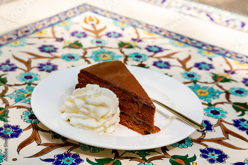 Apricot and chocolate Sacher cake with whipped cream. Sachertorte is a chocolate cake, or torte of Austrian origin, invented by Franz Sacher supposedly in 1832 for Prince Metternich in Vienna