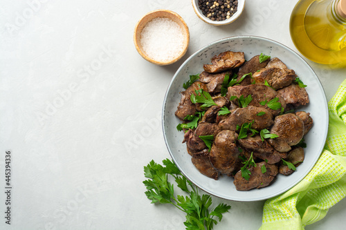 Fried chicken liver with parsley in plate on concrete background