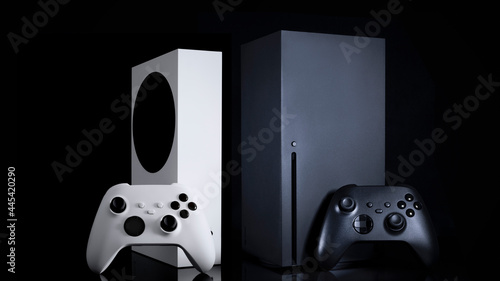 White and black game consoles and controllers with black background