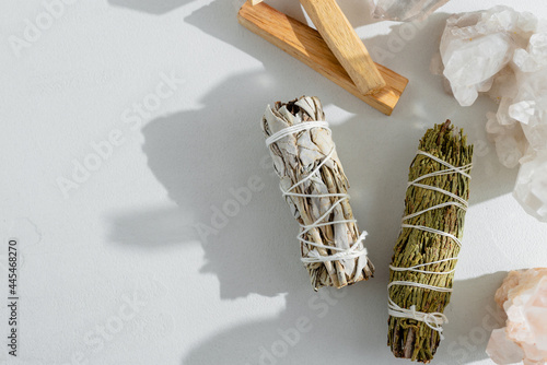 Set of incense for fumigating rooms beautifully lit by sunlight. Branches of white sage, Palo Santa sticks tied in bunch. Top view. Organic holy tree incense from America. Color photo close-up.
