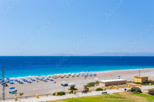 Colorful umbrellas and sunbeds on an empty beach resort - vacation concept on Greece islands in Aegean and Mediterranean seas. Elli Beach in Rhodes city.