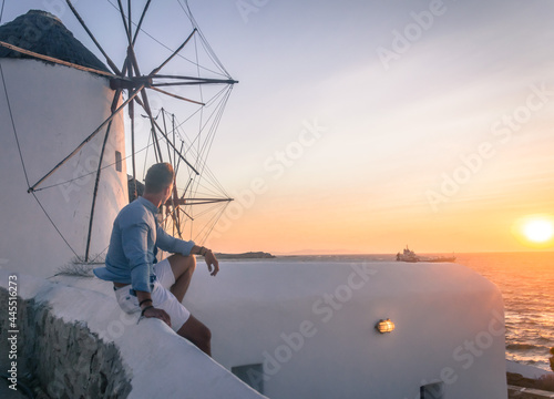 mężczyzna przy wiatraku patrzy na zachód słońca
