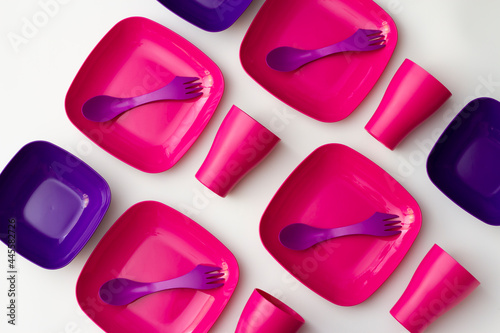 Purple plastic plates and forks with a spoon on a bluish background