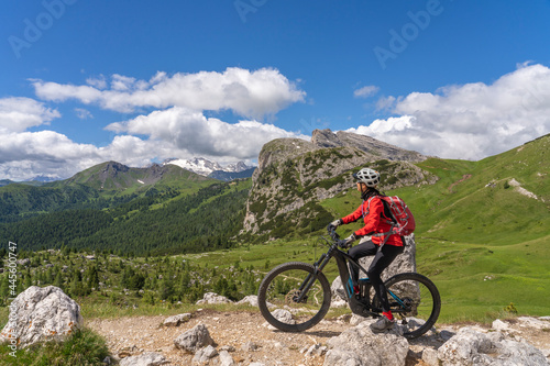 pretty active senior woman riding her electric mountain bike up to Valparola Pass in the Alta Badia Dolomites , South Tirol and Trentino, Italy
