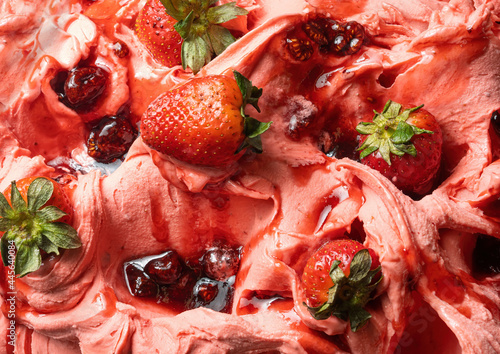 Frozen Strawberry flavour gelato - full frame detail. Close up of a pink surface texture of Ice cream covered with pieces of red fruit.