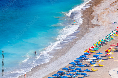 Colorful umbrellas and sunbeds on an empty beach resort - vacation concept on Greece islands in Aegean and Mediterranean seas. Akti Kanari Beach under Monte Smith in Rhodes city.