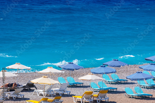 Colorful umbrellas and sunbeds on an empty beach resort - vacation concept on Greece islands in Aegean and Mediterranean seas