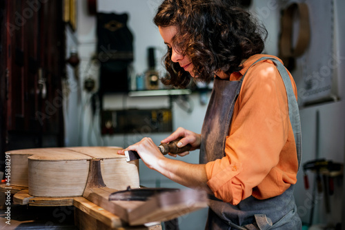 woman luthier making guitars in her musical instrument workshop