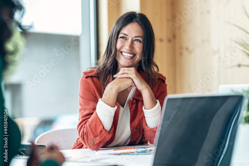 Smiling young business woman listening her partner on coworking space.