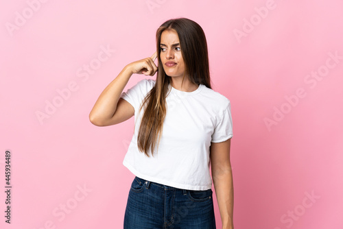 Young Uruguayan woman isolated on pink background making the gesture of madness putting finger on the head