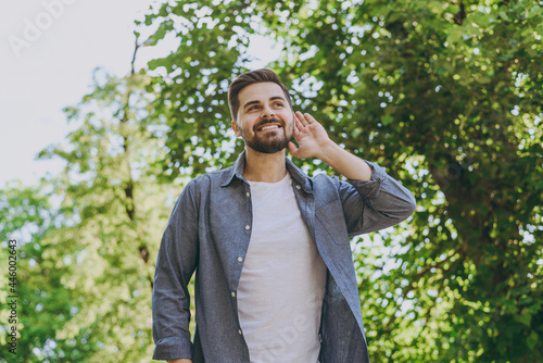 Bottom view young happy man in blue casual shirt walk try to hear chirping birds rest relax in spring green city park go down alley sunshine lawn outdoors on nature Urban lifestyle leisure concept