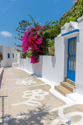 Traditional cycladitic alley with a narrow street, whitewashed houses and a blooming bougainvillea in Lagada, Amorgos Greece
