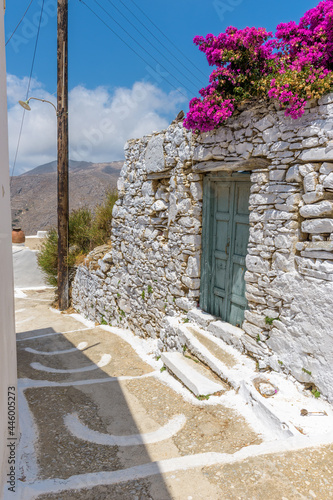 Traditional cycladitic alley with a narrow street, whitewashed houses and a blooming bougainvillea in Tholaria, Amorgos Greece