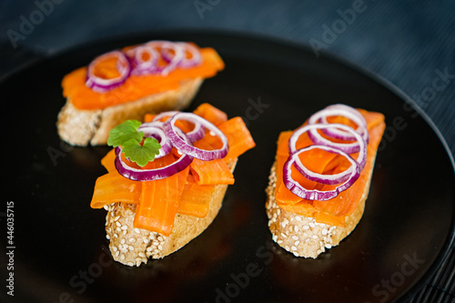 Carrot slices as fish substitute for smoked vegan salmon on whole wheat bread slices placed on a black plate