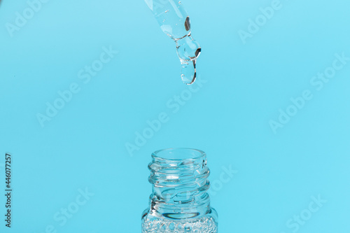 face serum drop with bottle on blue background.