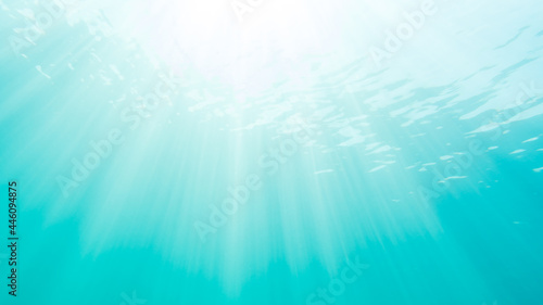 Sun rays shine through the water surface in summer