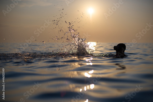 Młodzi przyjaciele kąpią się w morzu o zachodzie słońca. Sepia, backlight, silhouette.