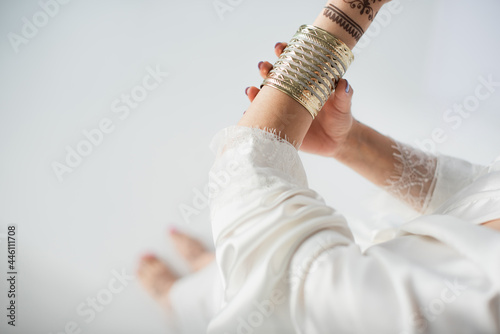 partial view of indian woman with mehndi on hands wearing golden bracelet while getting ready to wedding on white