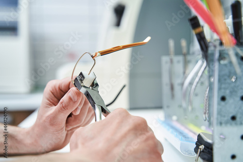 Male optician hands repairing eyeglasses in workshop