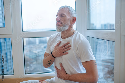 A mature yogi doing pranayama and looking meditative