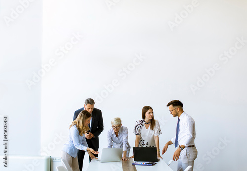 Group of business people with young adults and senior woman colleague on meeting at modern bright office interior