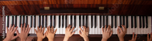 Young friends play the piano. Kids Hands touching piano keyboard