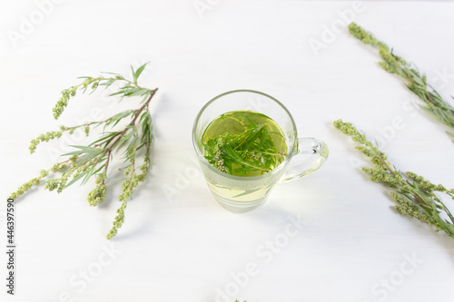 Cup with herbal tea of sagebrush on white background