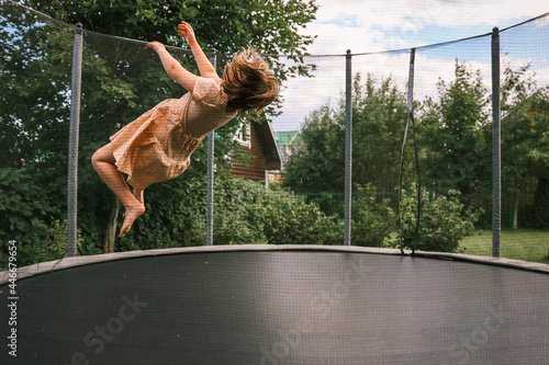 A girl jumps on a trampoline in the yard of the house