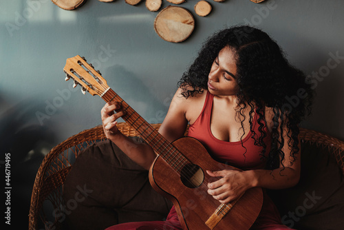 mujer negra de rizos con una guitarra tocando una melodía 