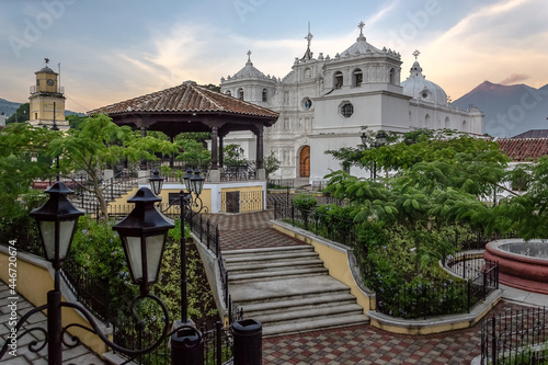 View of sunrise at the central park of Ciudad Vieja (Old City), second colonial capital of the Guatemala region. In the background the church of the city and behind the Fuego (Fire) active volcano