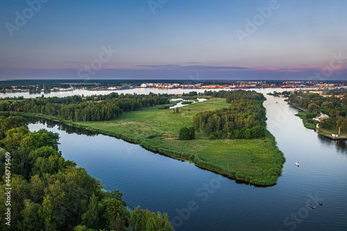 Riga port loading terminal with container ships. Boats and yachts riding on river. Industrial territory meets sustainable environment. 