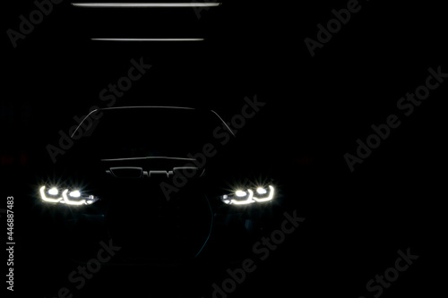 Unclear shape of front view sport car with headlights on dark background, Concept car concept, secret, new model car launch