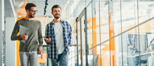 Two male co-workers chatting and walking in the building