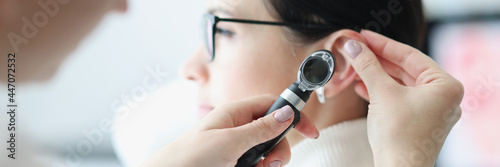 Otorhinolaryngologist examines patient ear with an otoscope