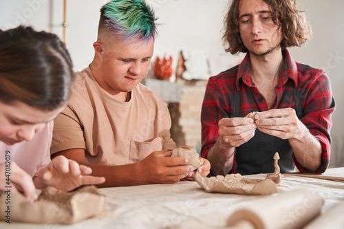 Craftsman teaching young people with special needs to make a plates from the clay