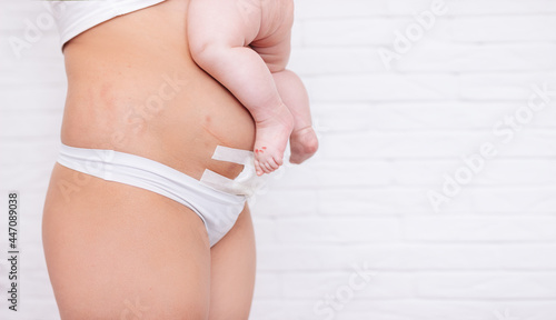 Slim and fit figure after cesarean section. a small child on the stomach of a woman after a cesarean section Close-up of a bandage on the stomach of a woman who underwent a cesarean section operation.