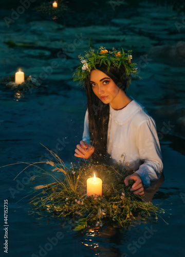 Pagan goddess. water lake, ritual flower wreaths float, candles burning. girl swims in riwer. white vintage shirt Holiday Ivan Kupala. Fantasy woman fortune telling predicts the future magic night