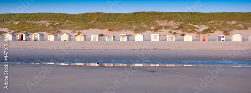 beach huts on dutch wadden island of texel at dusk under blue sky in summer