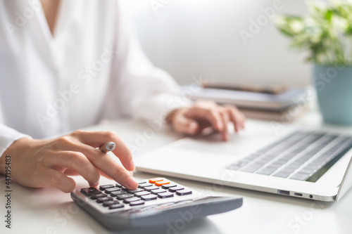 Woman entrepreneur using calculator, Saving money and calculating financial expense at home office concept.