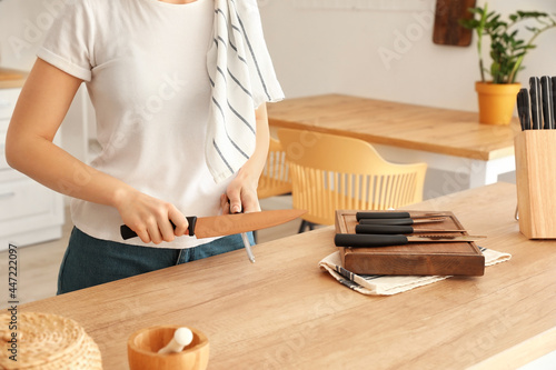 Woman sharpening knife in kitchen
