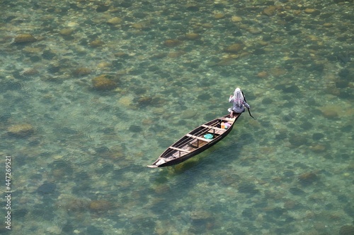 Fishing in transparent water of Dawki River in Meghalaya, India. River has crystal clear water in a lush environment and is a popular place for boating and kayaking